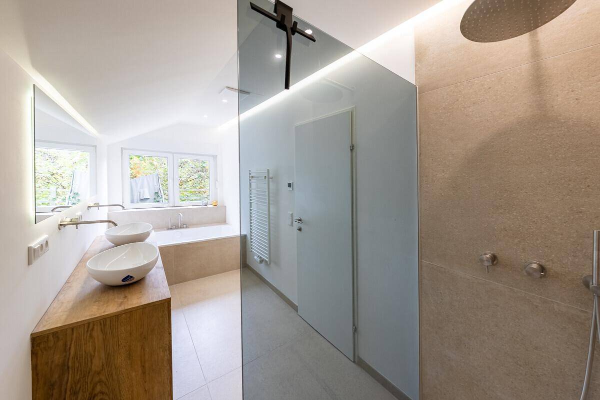 Modernes Badezimmer mit Doppelwaschbecken, begehbarer Dusche und Badewanne am Fenster.