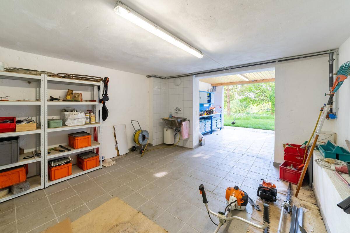 Geräumiger Werkstatt- oder Lagerraum mit Regalen, Fliesenboden und Zugang zum Außenbereich.