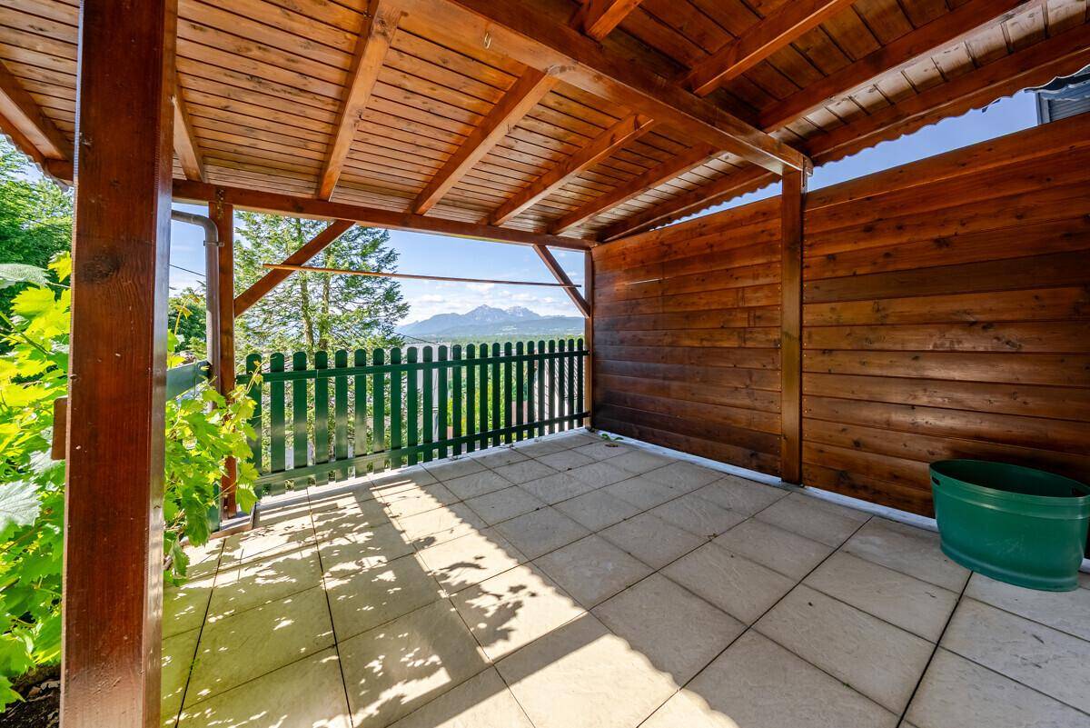 Überdachte Terrasse mit Fliesenboden und Holzwänden, bietet einen schönen Bergblick.