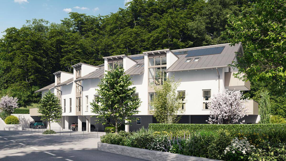 Neubau-Reihenhäuser mit moderner Architektur, umgeben von gepflegten Grünflächen und Bäumen.