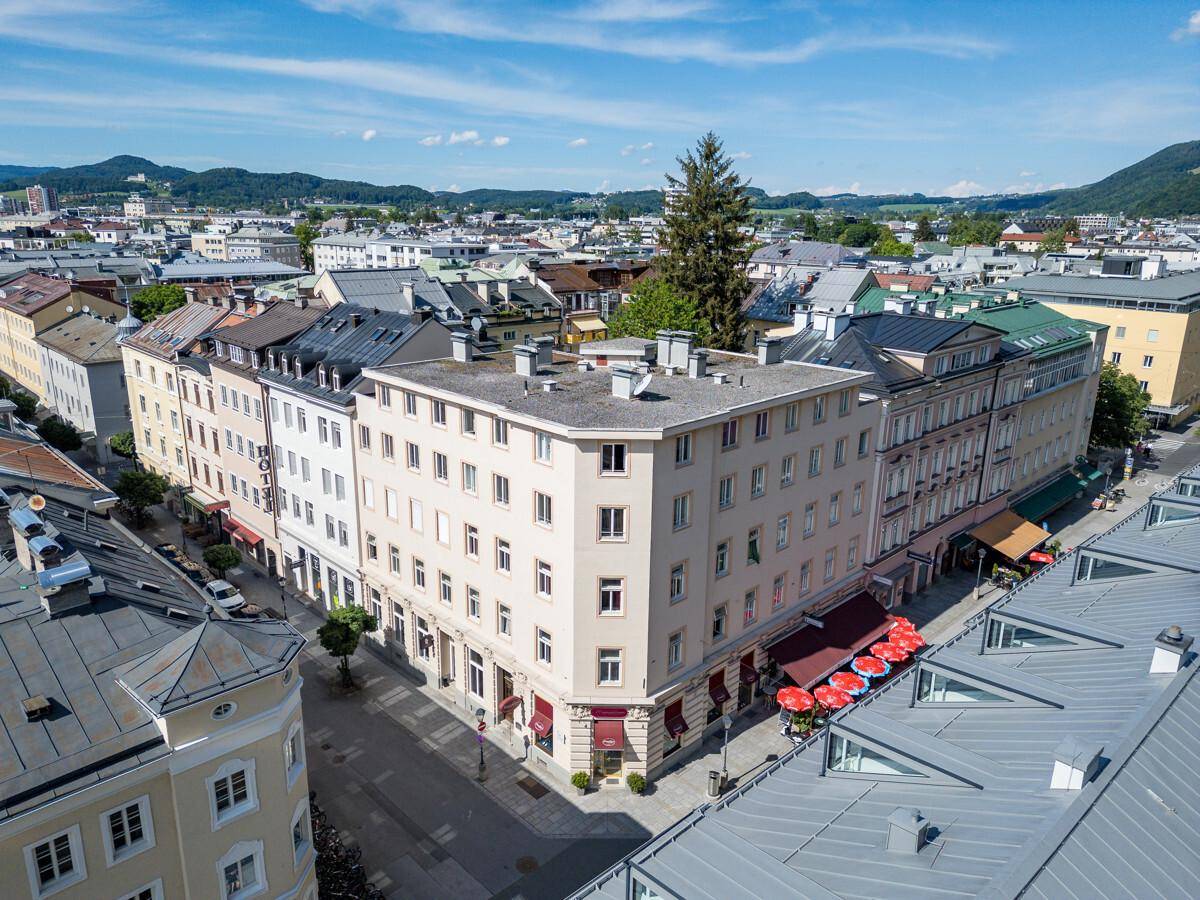 Weitläufige Luftaufnahme einer historischen Stadt mit vielen Gebäuden, Straßen und Bergen im Hintergrund.