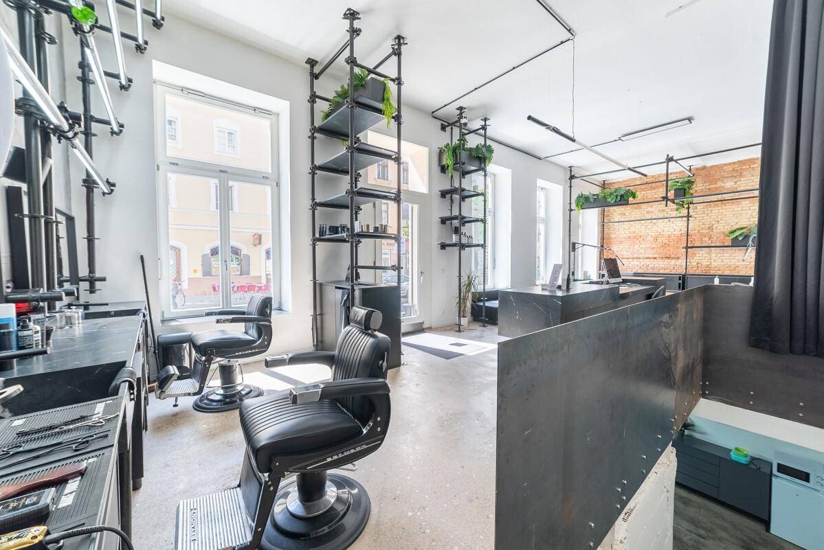 Friseurbereich in einem modernen Studio mit Stühlen, industriellen Regalen und Blick auf die Straße.