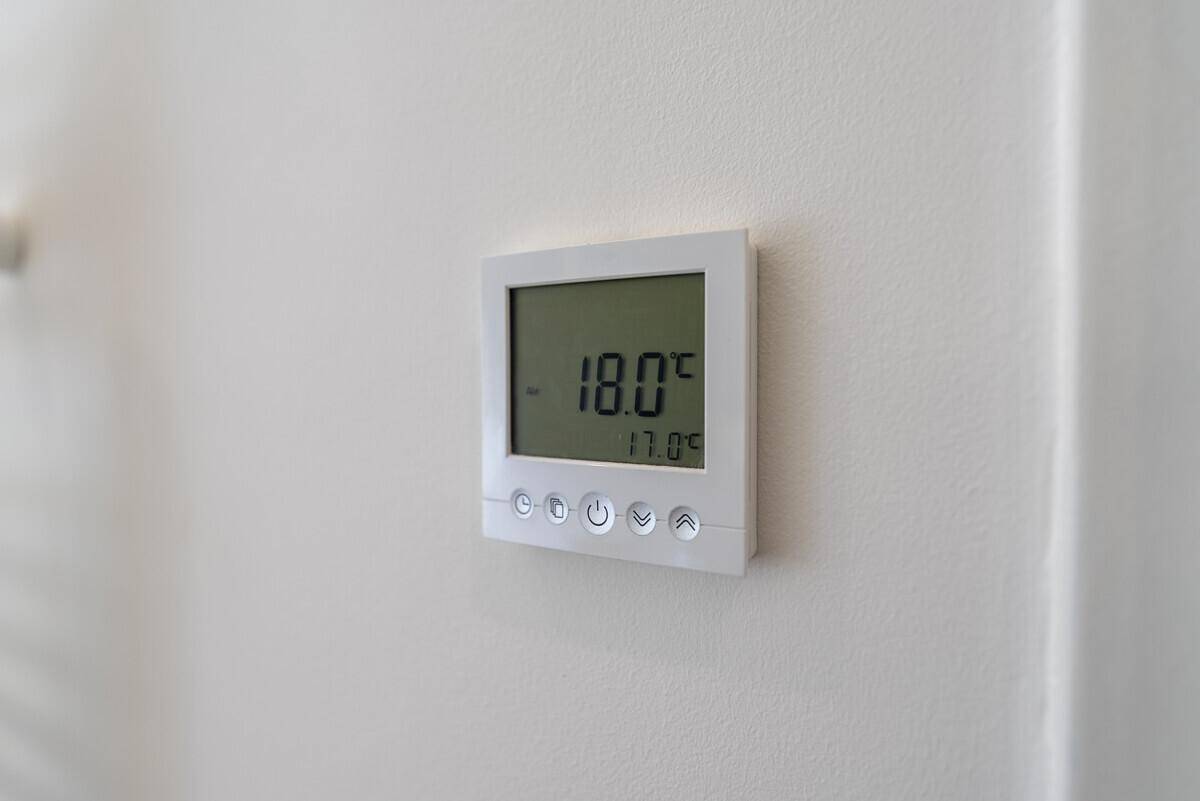 Digitaler Thermostat an einer weißen Wand zur Steuerung der Raumtemperatur.