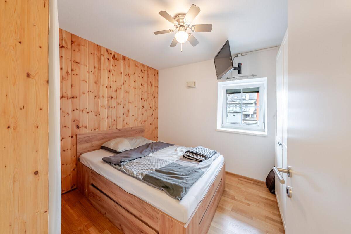 Schlafzimmer mit Holzwand, Doppelbett und Deckenventilator für angenehmes Klima.