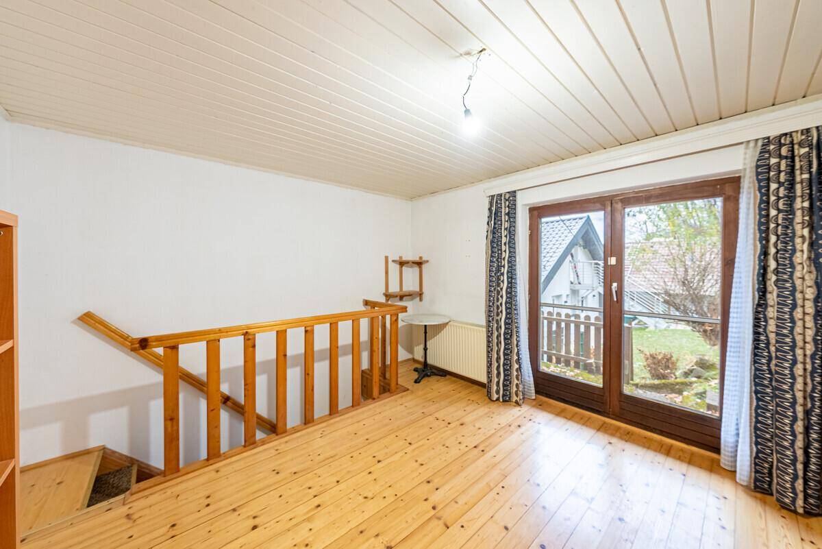 Heller Raum mit Holzfußboden und Treppenzugang, bietet vielseitige Nutzungsmöglichkeiten.
