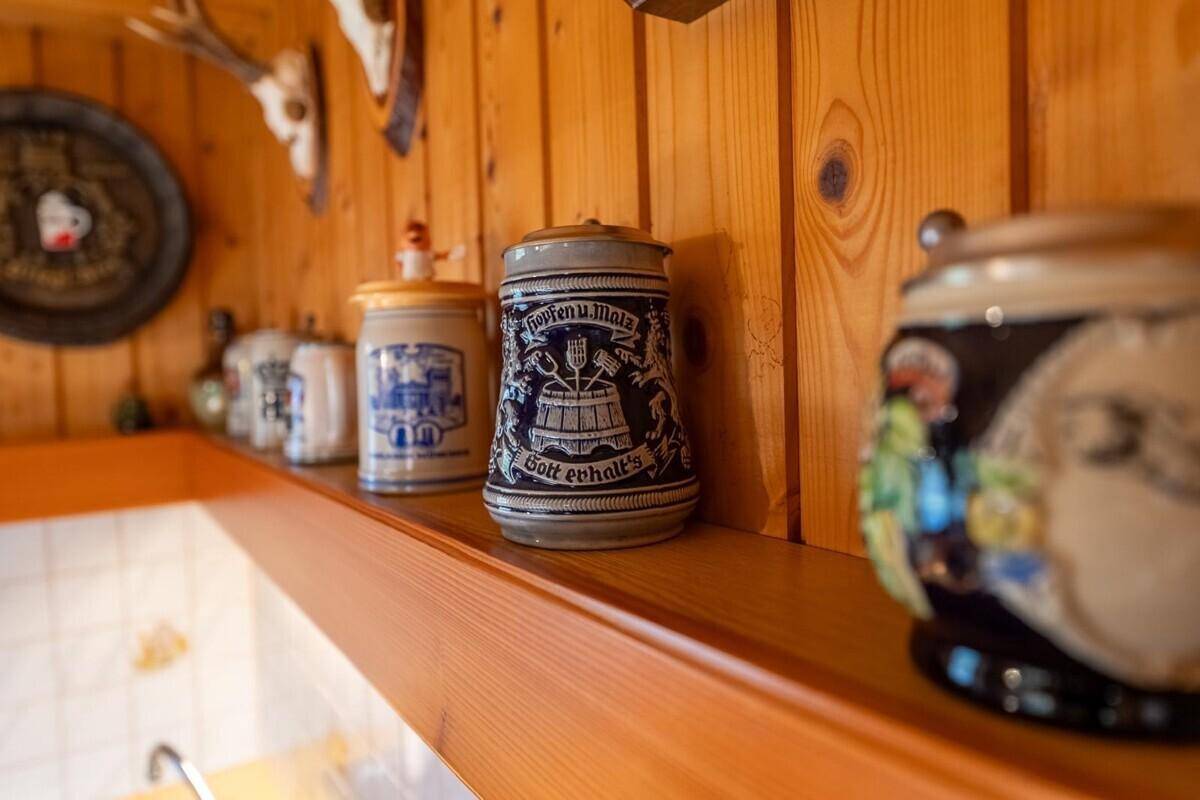 Traditionelle Dekoration mit Bierkrügen und Hirschgeweih an der Holzwand der Küche.