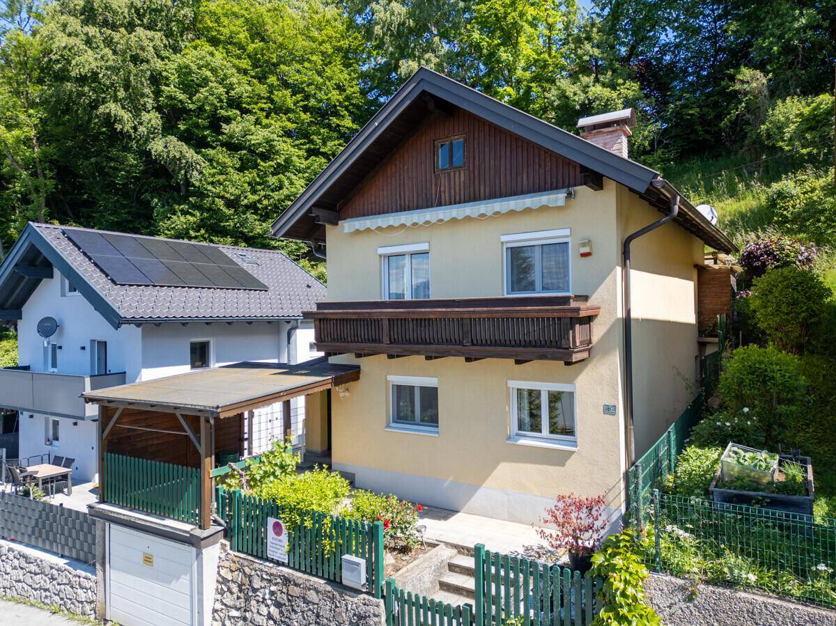 Freistehendes Haus mit Balkon und Carport, umgeben von einem gepflegten Garten.