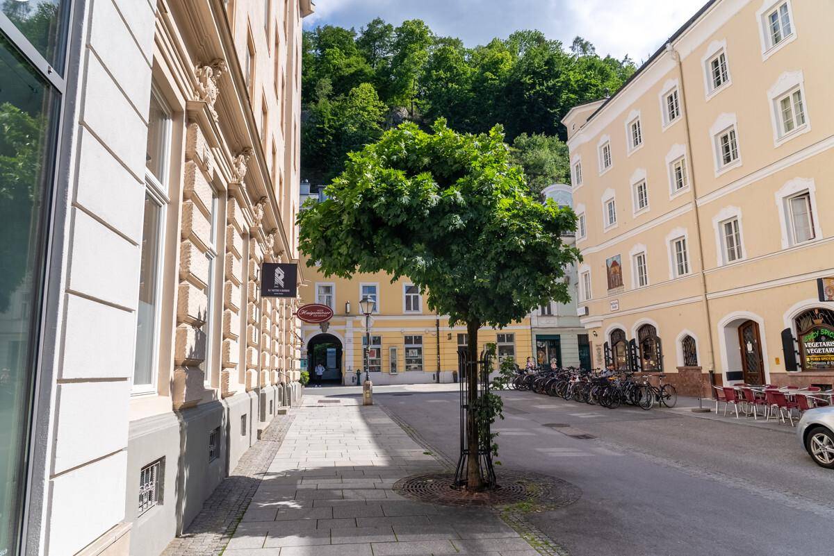 Malerische Gasse mit traditionellen Gebäuden, einem Baum und Fahrrädern in einer europäischen Stadt.
