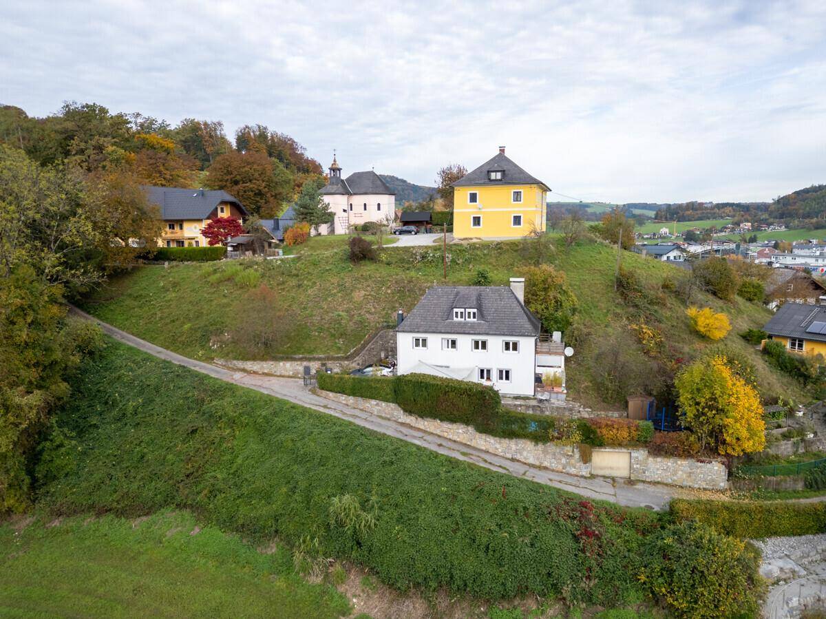 Luftaufnahme des Anwesens mit umliegender Hügellandschaft und weiteren Gebäuden.
