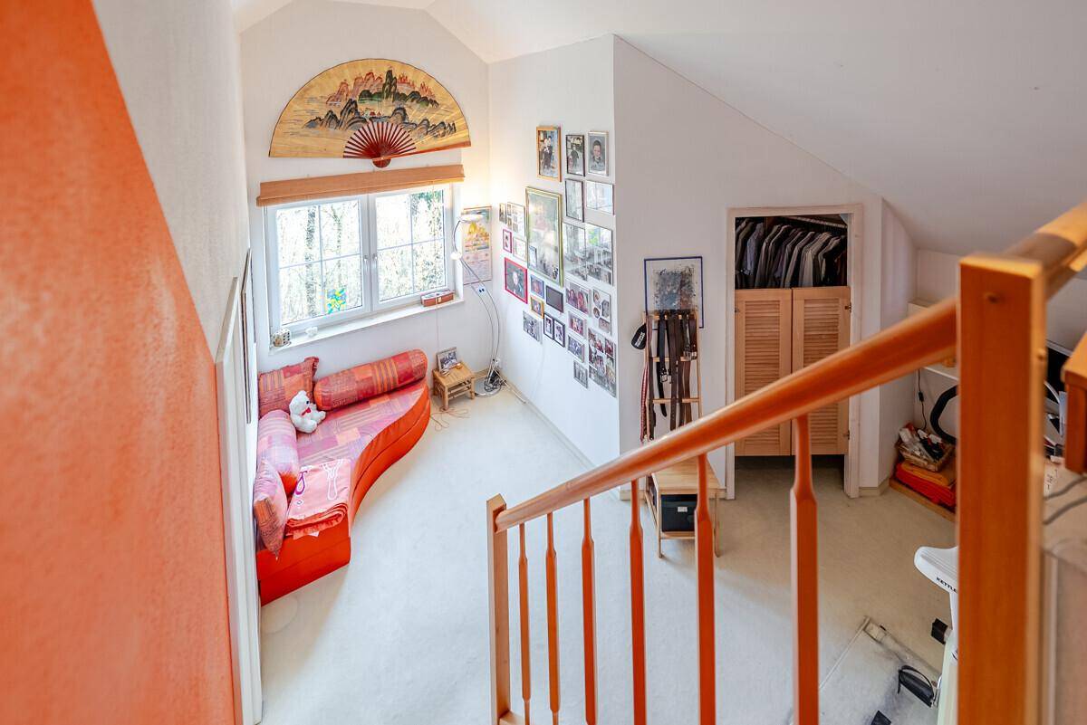Blick vom oberen Treppenabsatz auf den hellen Flur und den Wohnbereich mit Sofa.