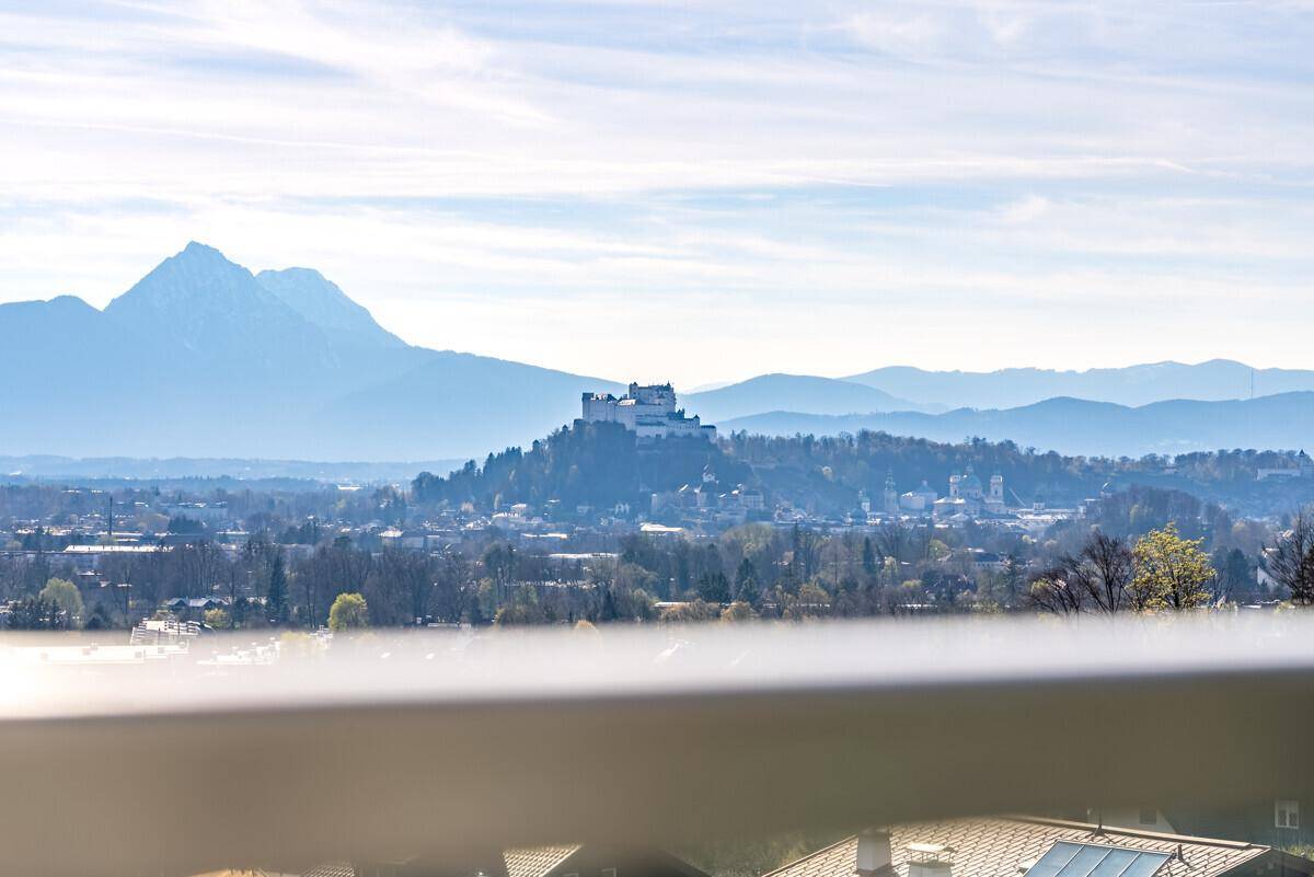 Panoramablick von der Terrasse auf die Stadt Salzburg mit der Festung Hohensalzburg und den Bergen.
