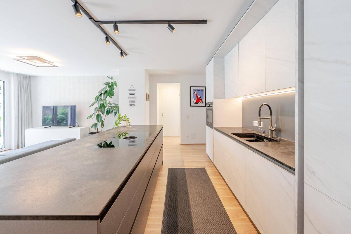 Moderne Küche mit großer Kücheninsel, integriertem Kochfeld und eleganten weißen Schränken.