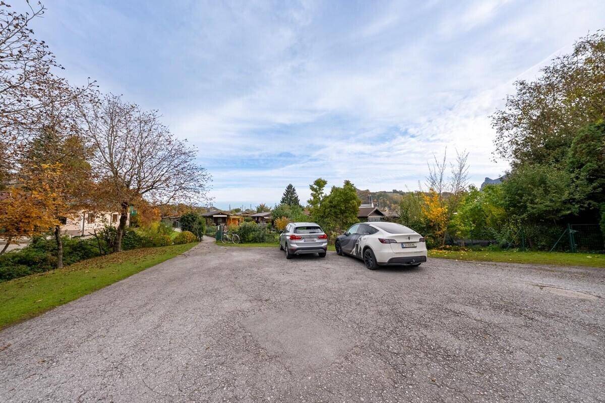 Großer Außenparkplatz mit zwei Fahrzeugen, umgeben von Bäumen und ländlicher Umgebung.
