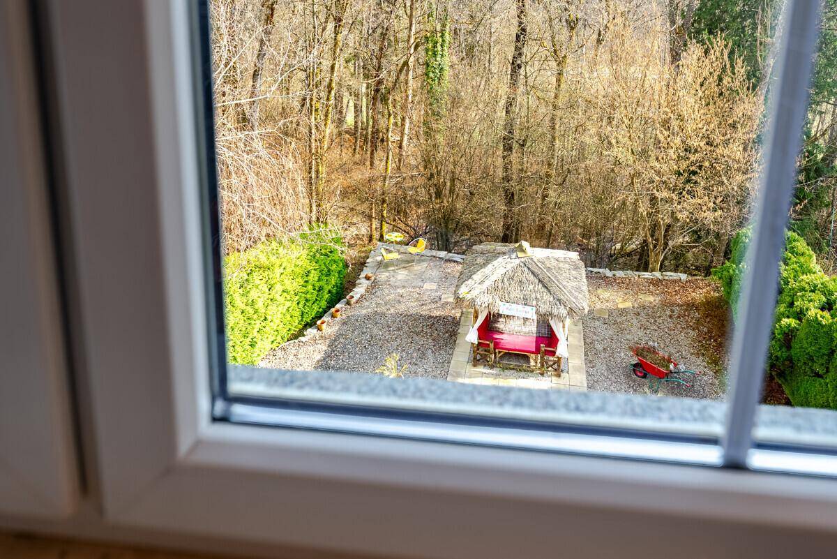 Blick aus dem Fenster auf den Kiesgarten mit Stroh-Pavillon und die umliegende Natur.