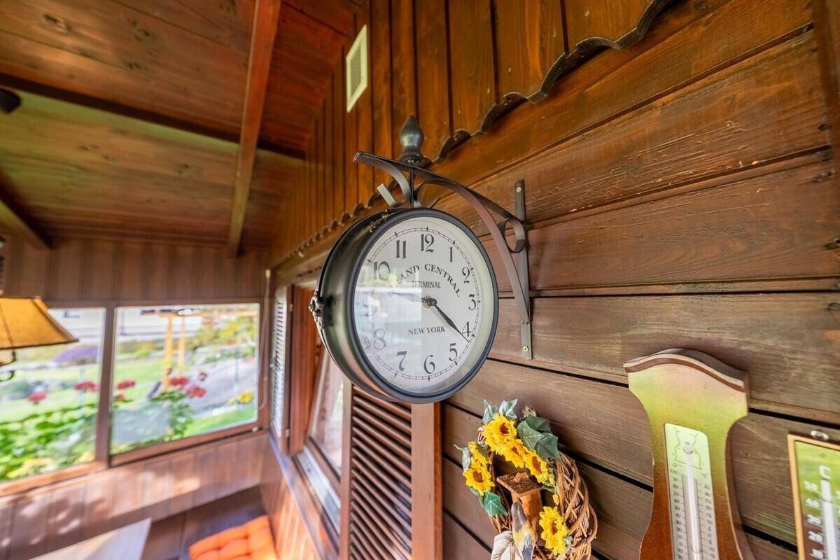 Detailaufnahme einer dekorativen Bahnhofsuhr an der Holzwand im Wintergarten.