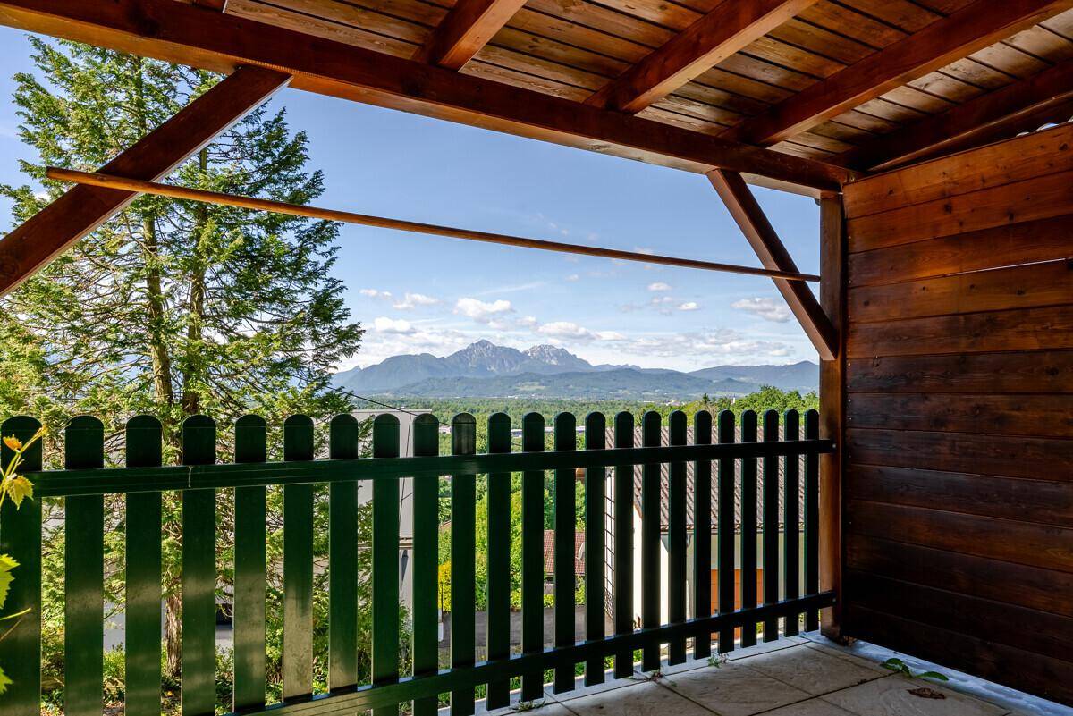 Überdachter Terrassenbereich mit Holzzaun und weitem Blick auf die umliegende Bergwelt.