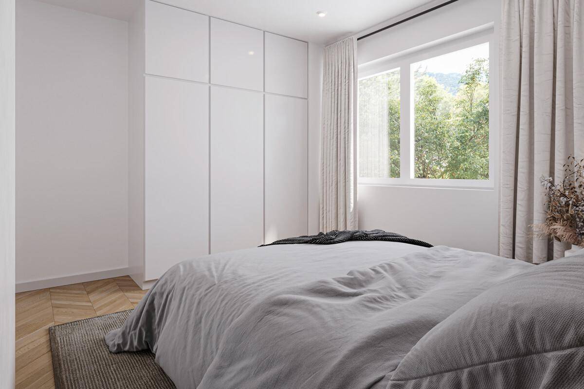 Schlafzimmer mit großen weißen Einbauschränken, Parkettboden und Blick ins Grüne.