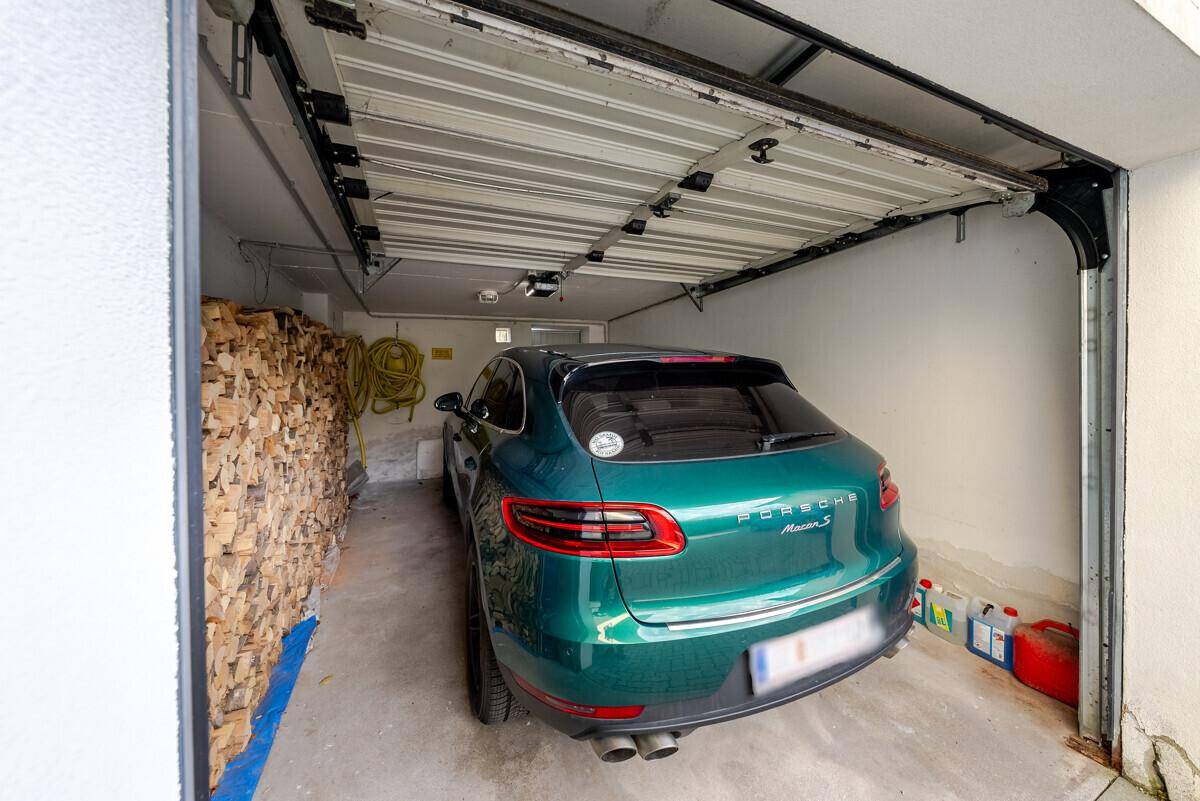 Geräumige Garage mit einem geparkten Auto und gestapeltem Brennholz.