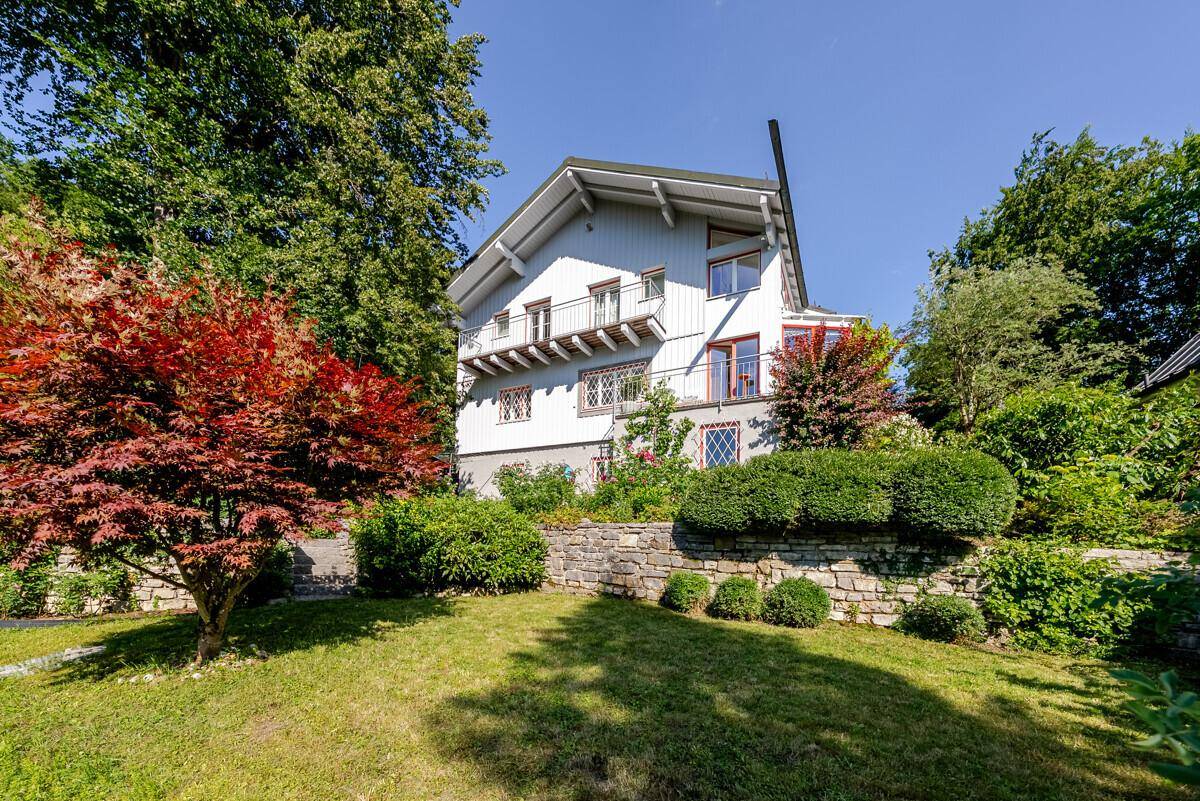 Ansicht des Hauses von einem gepflegten Garten mit üppiger Vegetation und Steinmauern.