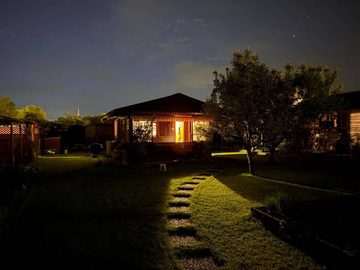 Beleuchteter Gartenweg führt bei Nacht zu einem gemütlichen Holzhaus mit warmem Licht.