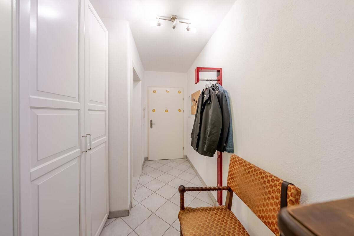 Heller Flur mit weißen Einbauschränken, Fliesenboden und Garderobe.