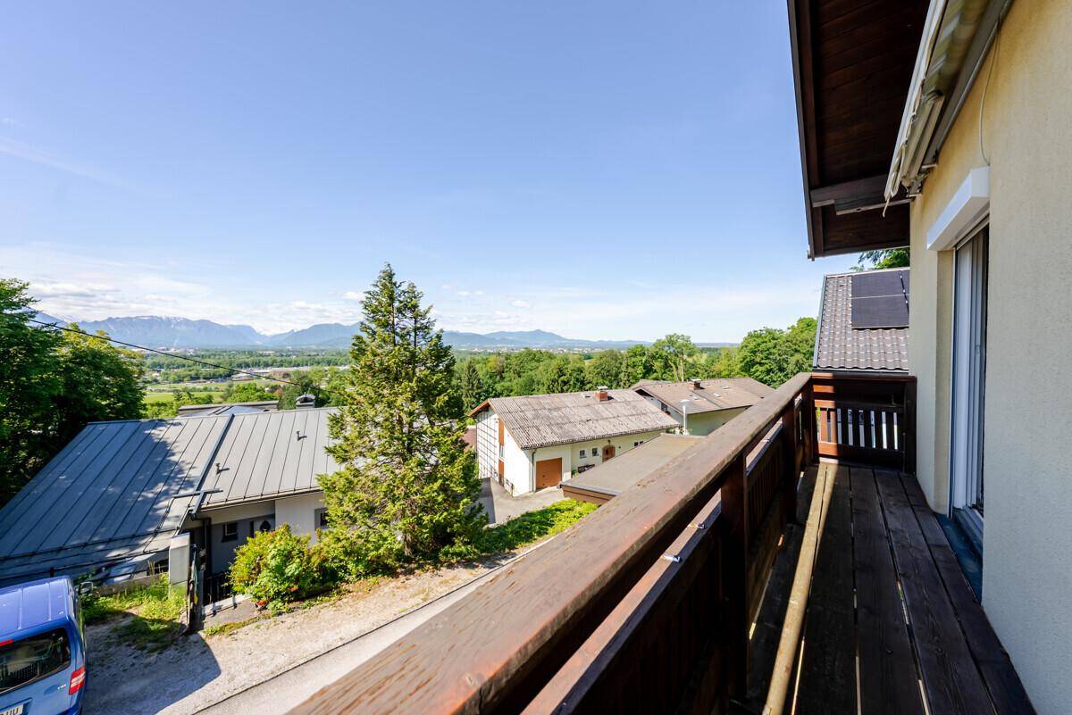 Blick vom Balkon auf die Nachbarschaft und die umliegende grüne Landschaft mit Bergen.