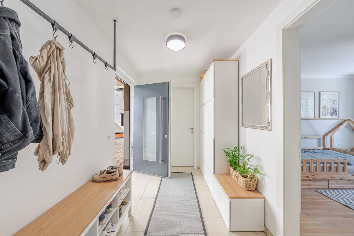 Heller Eingangsbereich mit Garderobe, Schuhregal und Sitzbank, einladend gestaltet.
