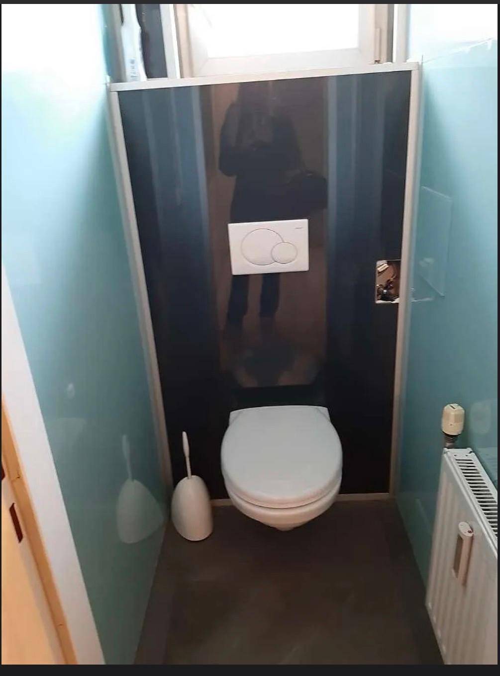 Separates WC mit wandhängender Toilette, Heizkörper und hellblauen Wandpaneelen.