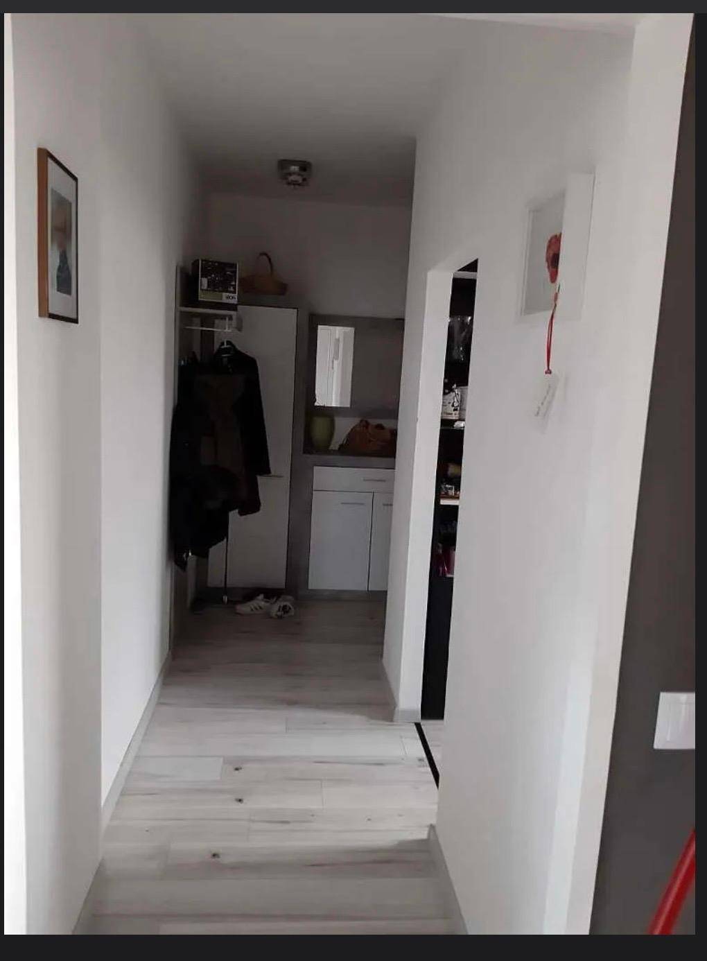 Heller Flur mit modernem Laminatboden und weiß gestrichenen Wänden, der zu weiteren Räumen führt.