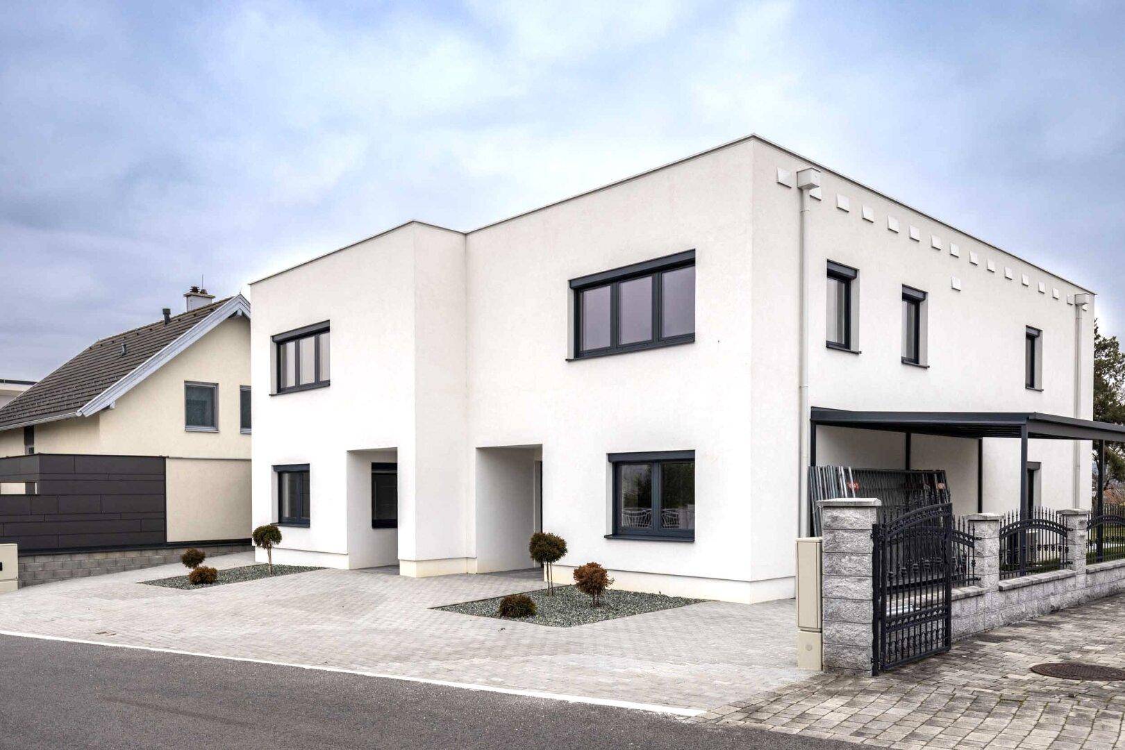 Ansicht der modernen Doppelhaushälfte mit klaren Linien und dunklen Fensterrahmen.