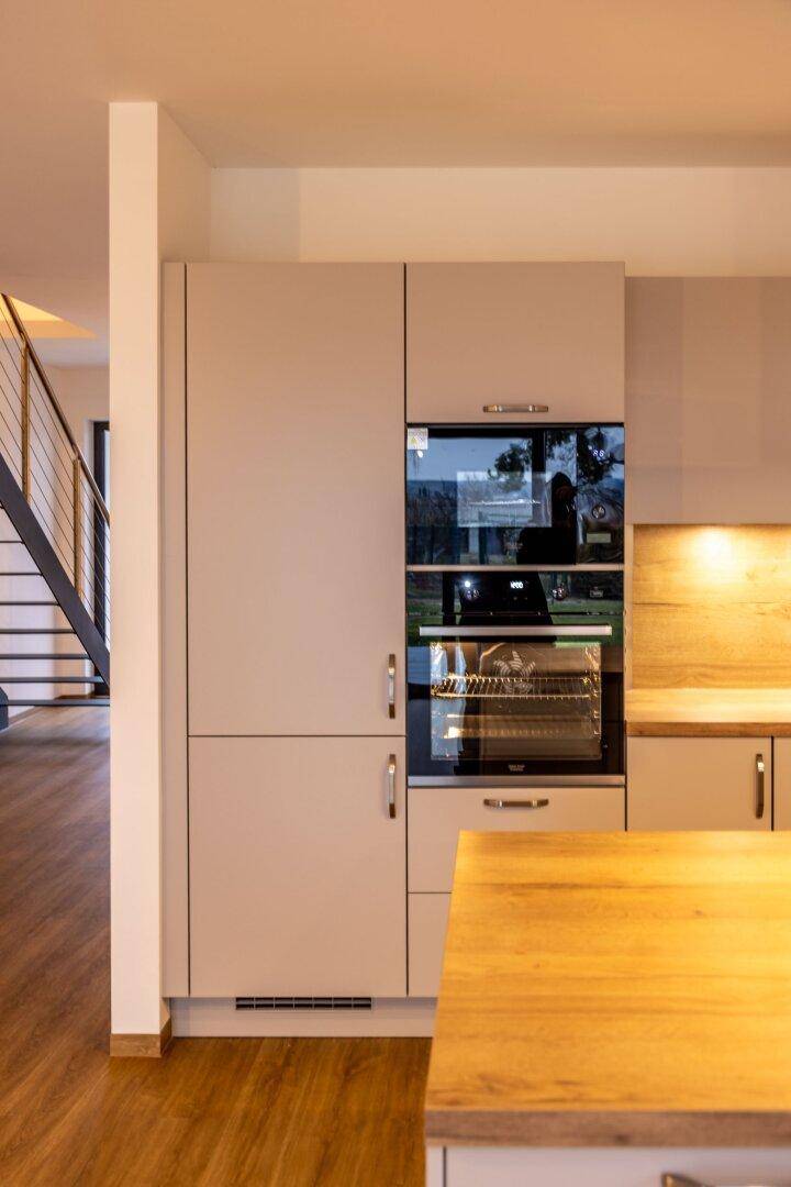 Integrierte Backöfen und Mikrowelle in der modernen Einbauküche mit Holzdetails.