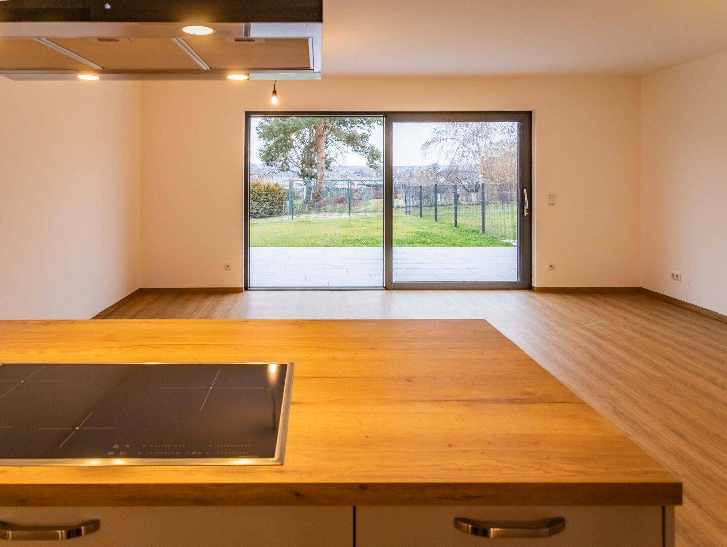 Blick von der Küche durch große Schiebetüren auf den grünen Gartenbereich.