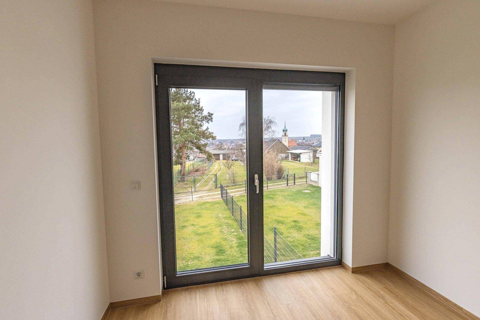 Heller Raum mit großem Fenster und weitem Blick auf den Garten und die Umgebung.