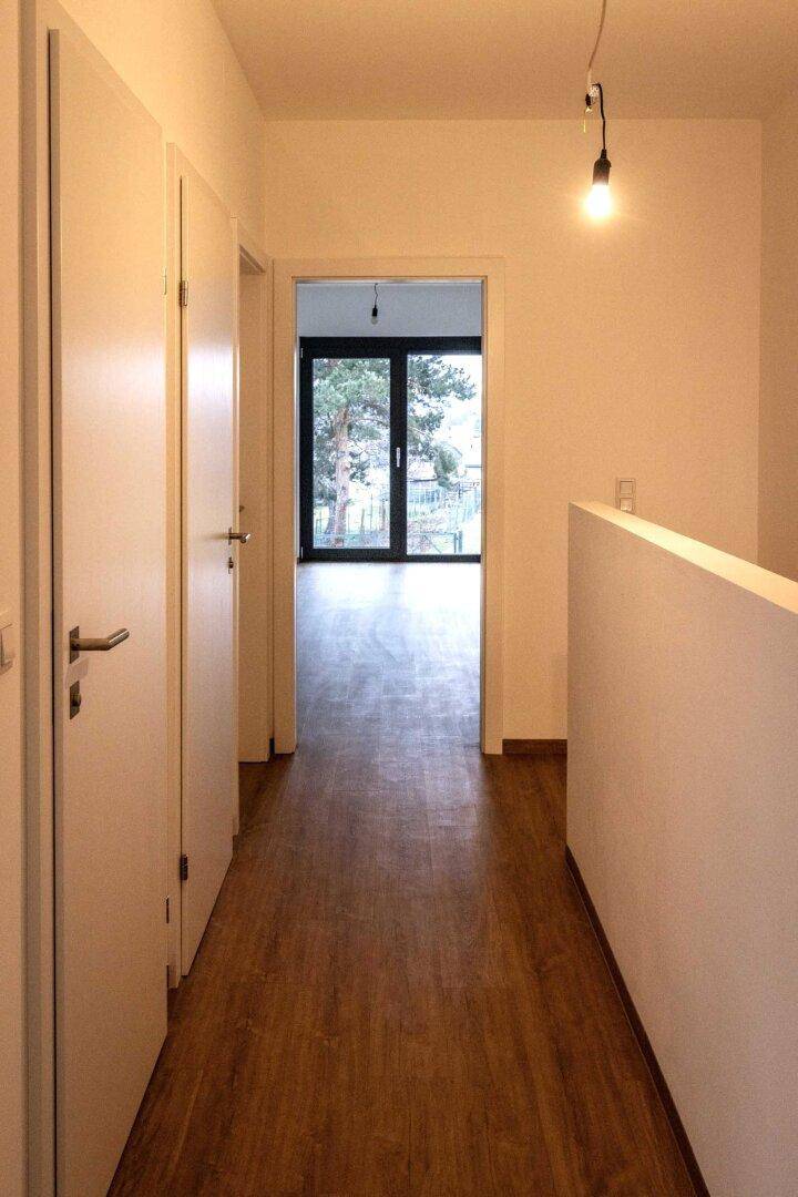 Heller Flur mit mehreren Türen und Blick in einen Raum mit Gartenzugang.
