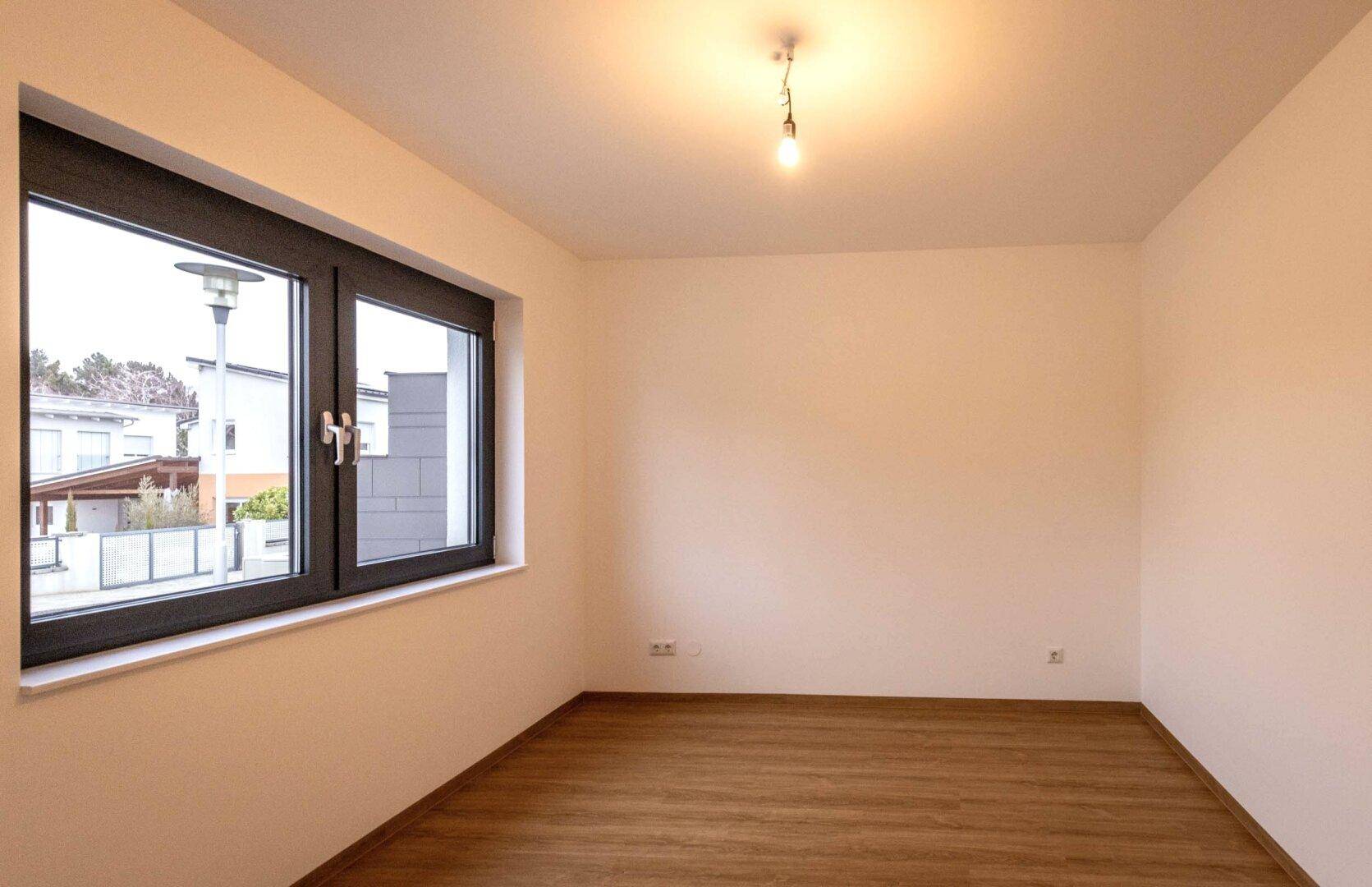 Heller Raum mit großem Fenster und Blick auf die Straße und Nachbarschaft.