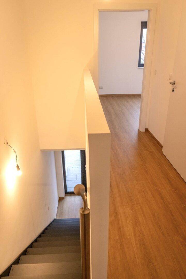 Moderner Treppenaufgang mit Geländer und Blick in den unteren Bereich.