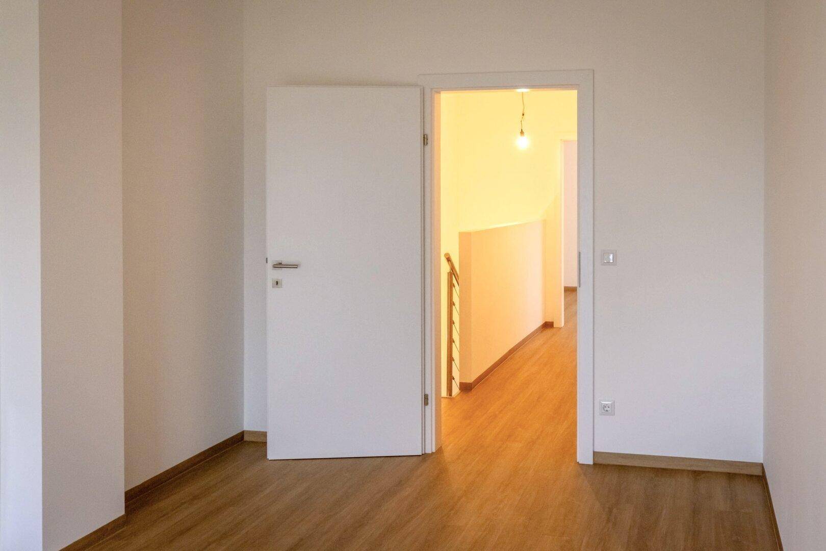 Heller Raum mit Laminatboden und offener Verbindung zum Flurbereich.