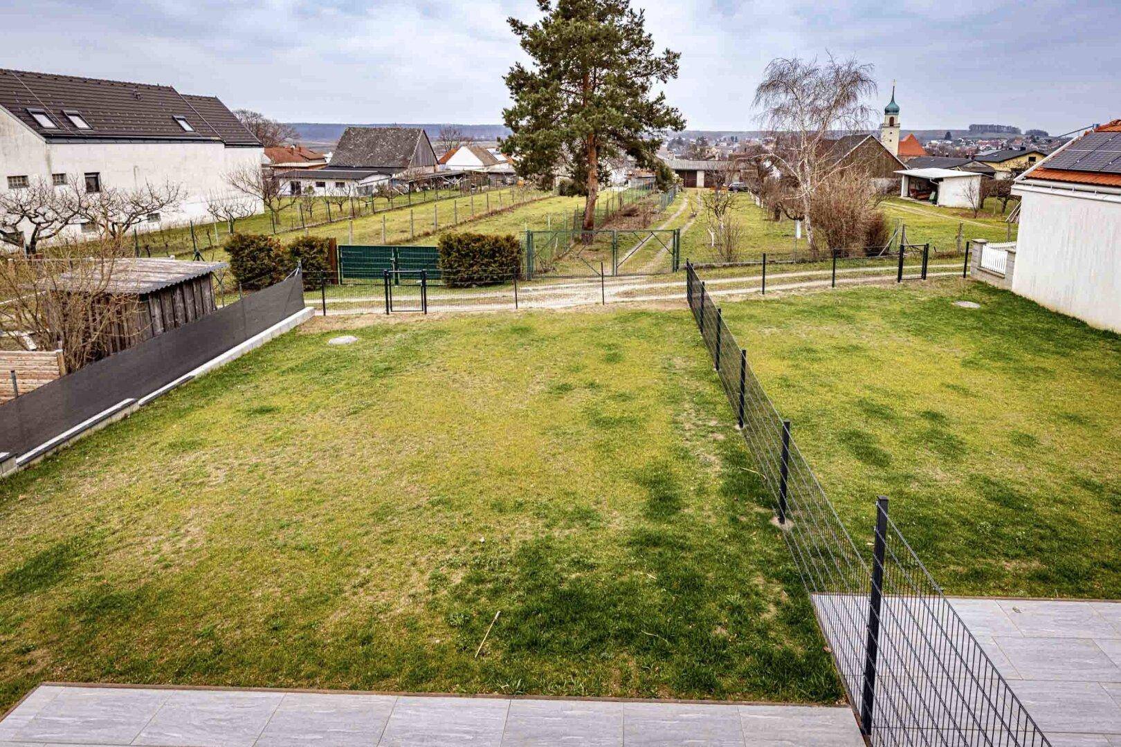 Große Rasenfläche im Garten mit Blick auf die Nachbarschaft und die Kirche.