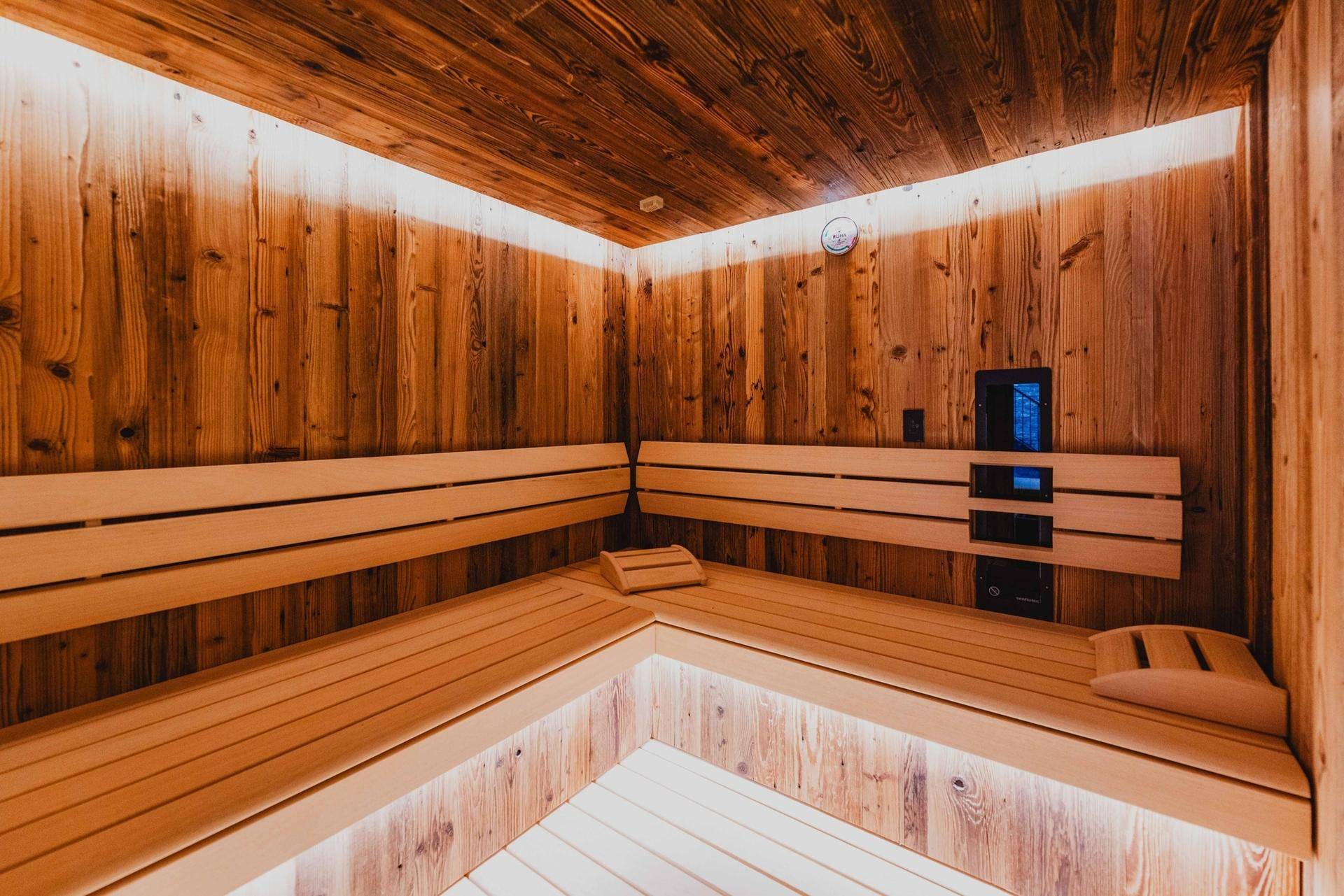 Geräumige Sauna mit mehreren Holzbänken und stimmungsvoller Beleuchtung.