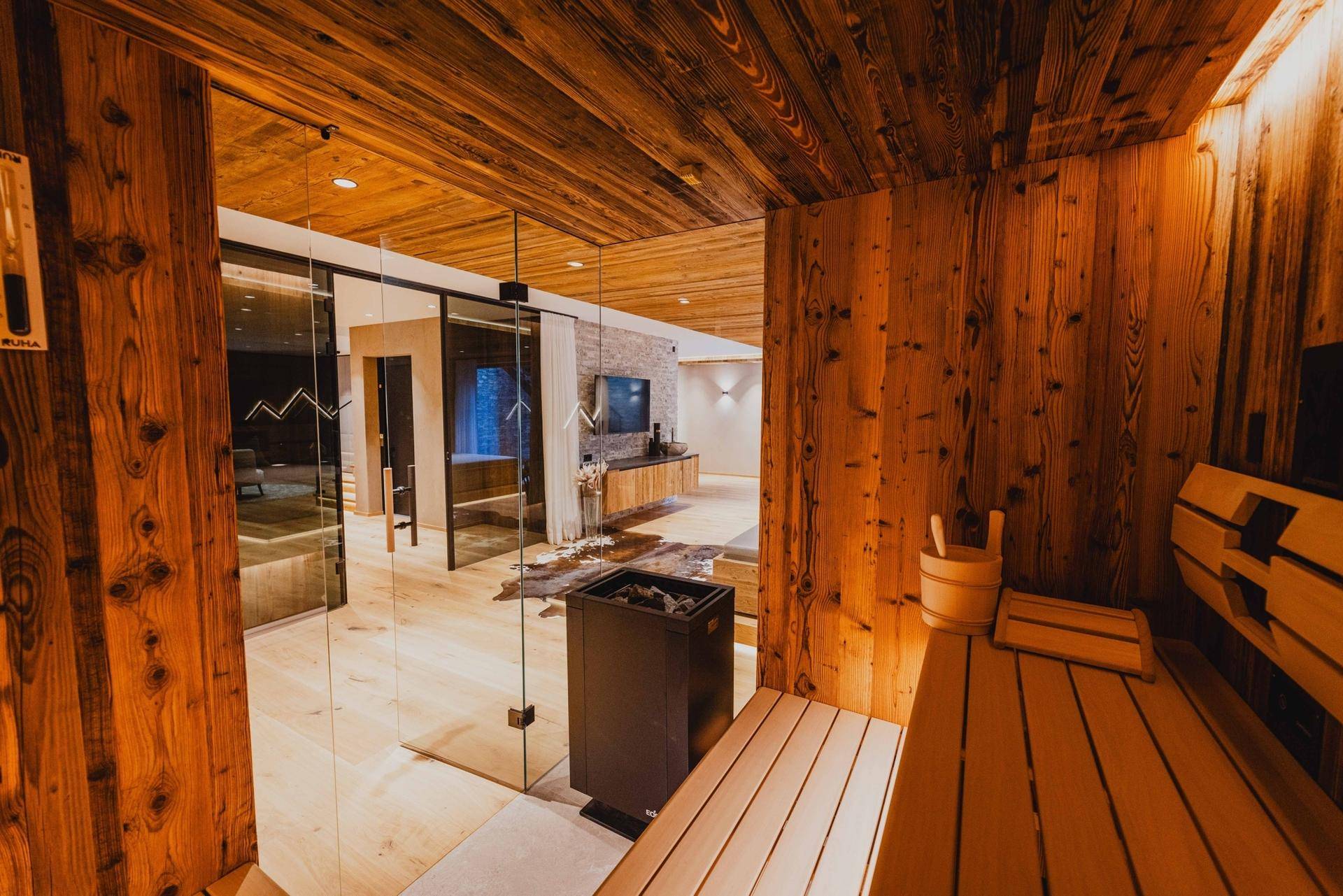 Blick aus der Sauna in den Wellnessbereich mit Liegebetten und Holzelementen.