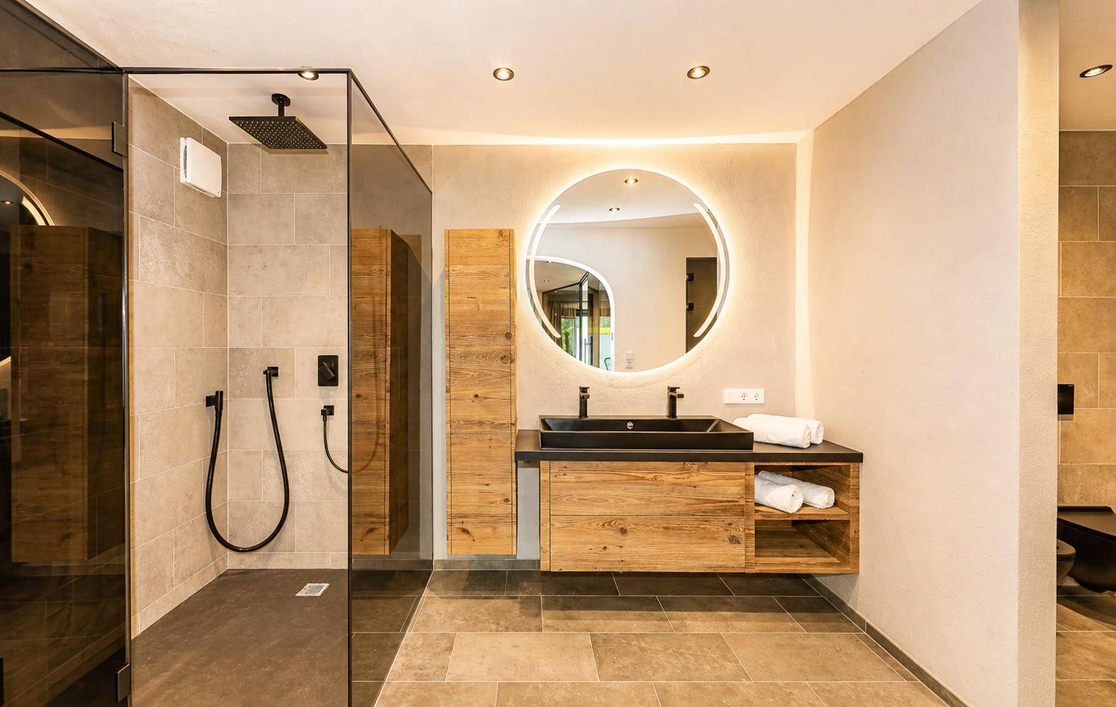 Modernes Badezimmer mit begehbarer Dusche, Einzelwaschbecken und beleuchtetem Spiegel.