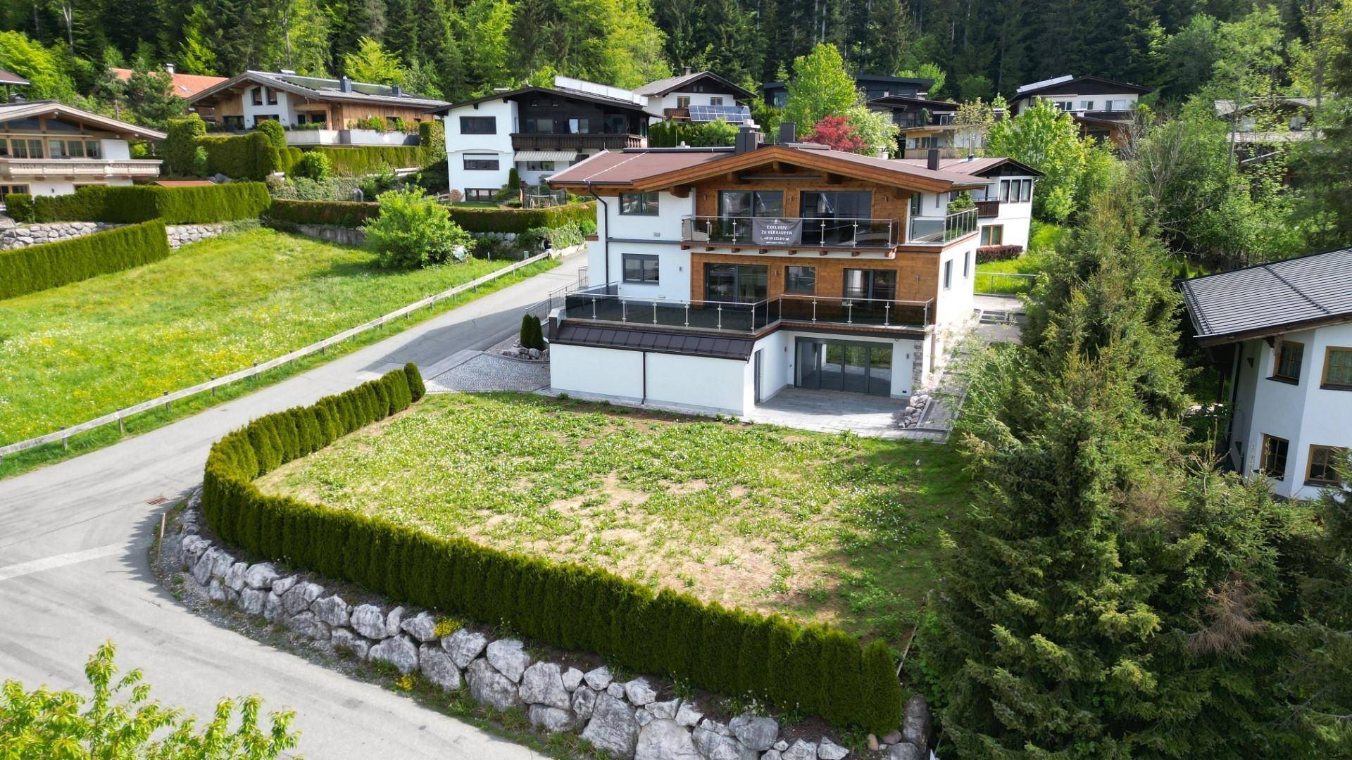 Freistehendes Wohnhaus mit großem Gartenbereich und Blick auf die grüne Umgebung und Berge.