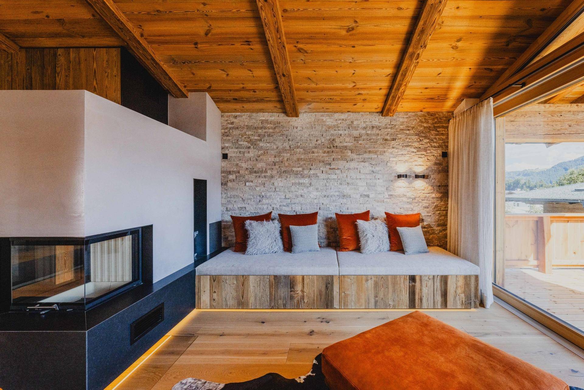 Gemütliche Sitzecke mit Kamin, Steinwand und Holzboden, ideal zum Entspannen.