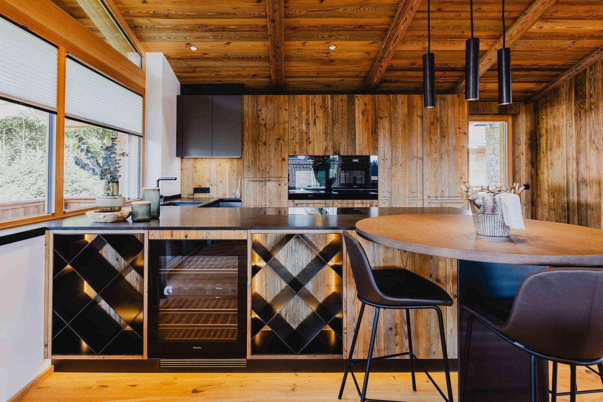 Moderne Holzküche mit integrierten Geräten, Weinkühler und Bartresen für gesellige Stunden.