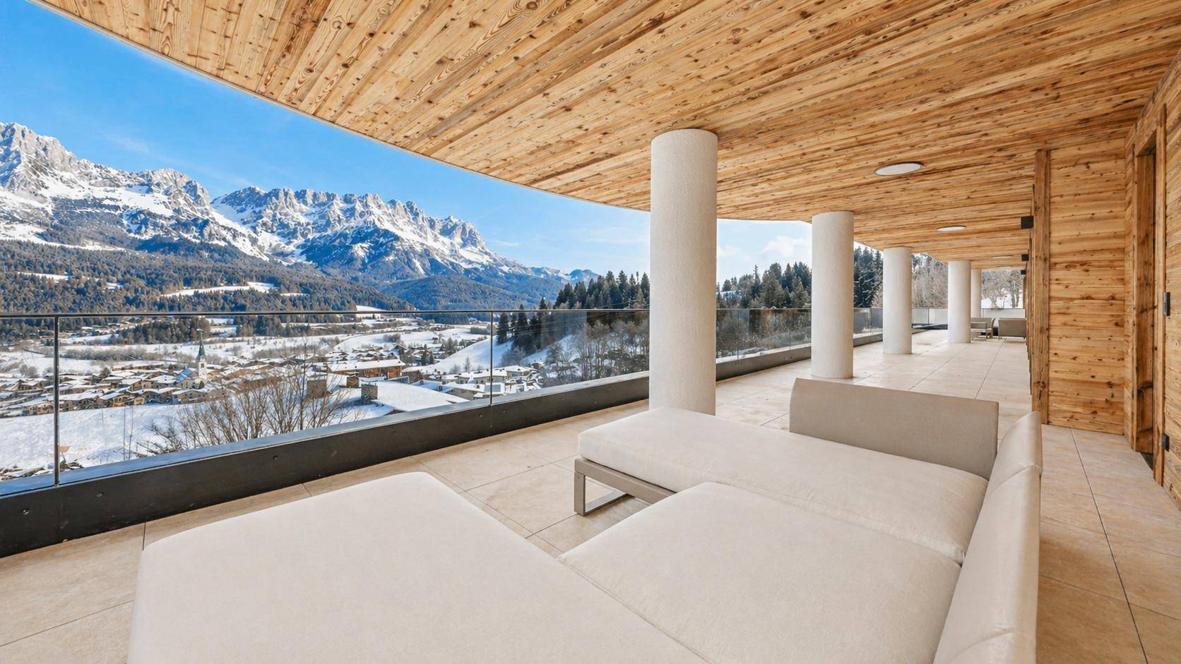 Weitläufige Terrasse mit bequemen Liegen und Panoramablick auf die verschneiten Berge.