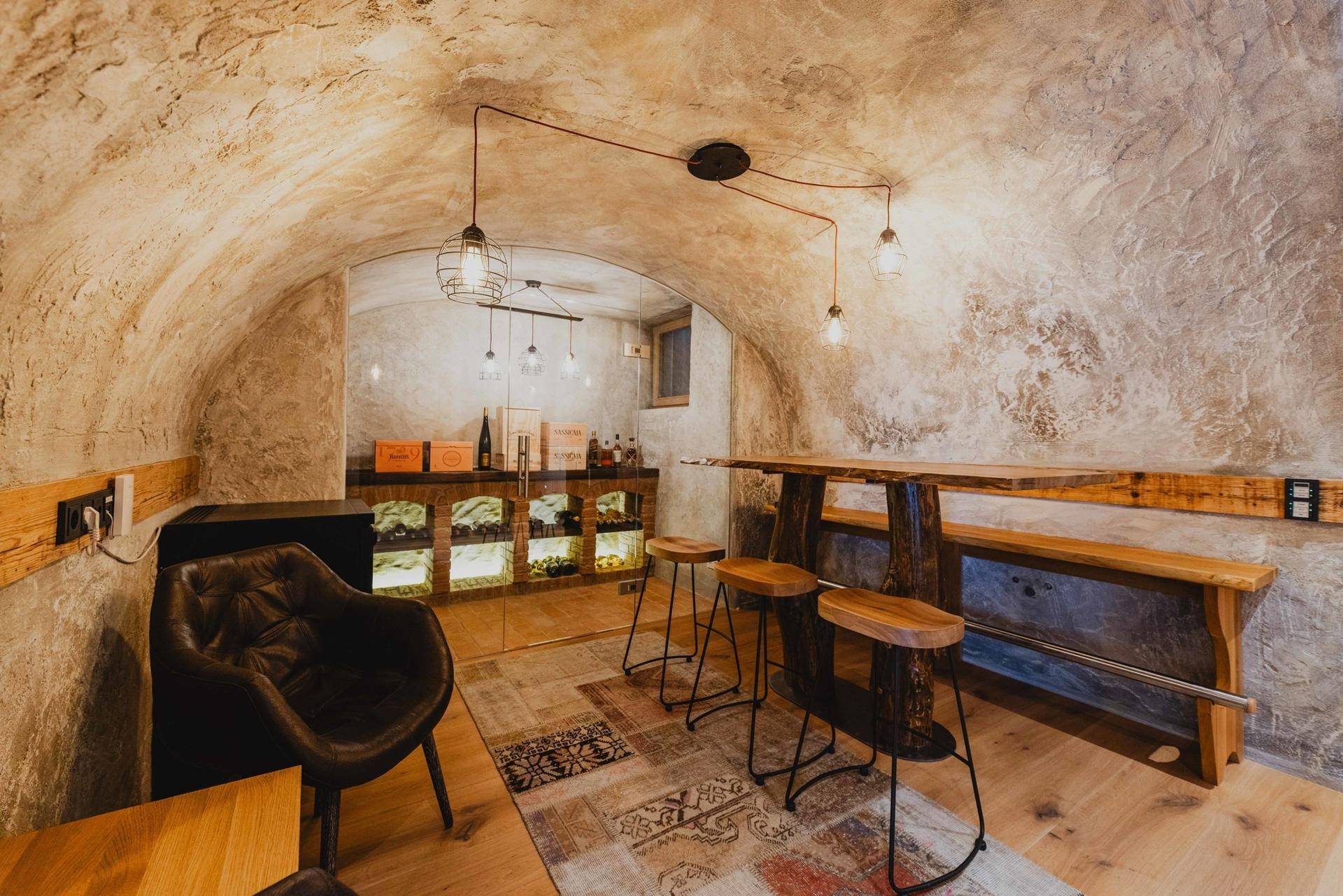 Rustikaler Weinkeller mit Gewölbedecke, Holztisch und Barhockern, ideal für Weinproben.