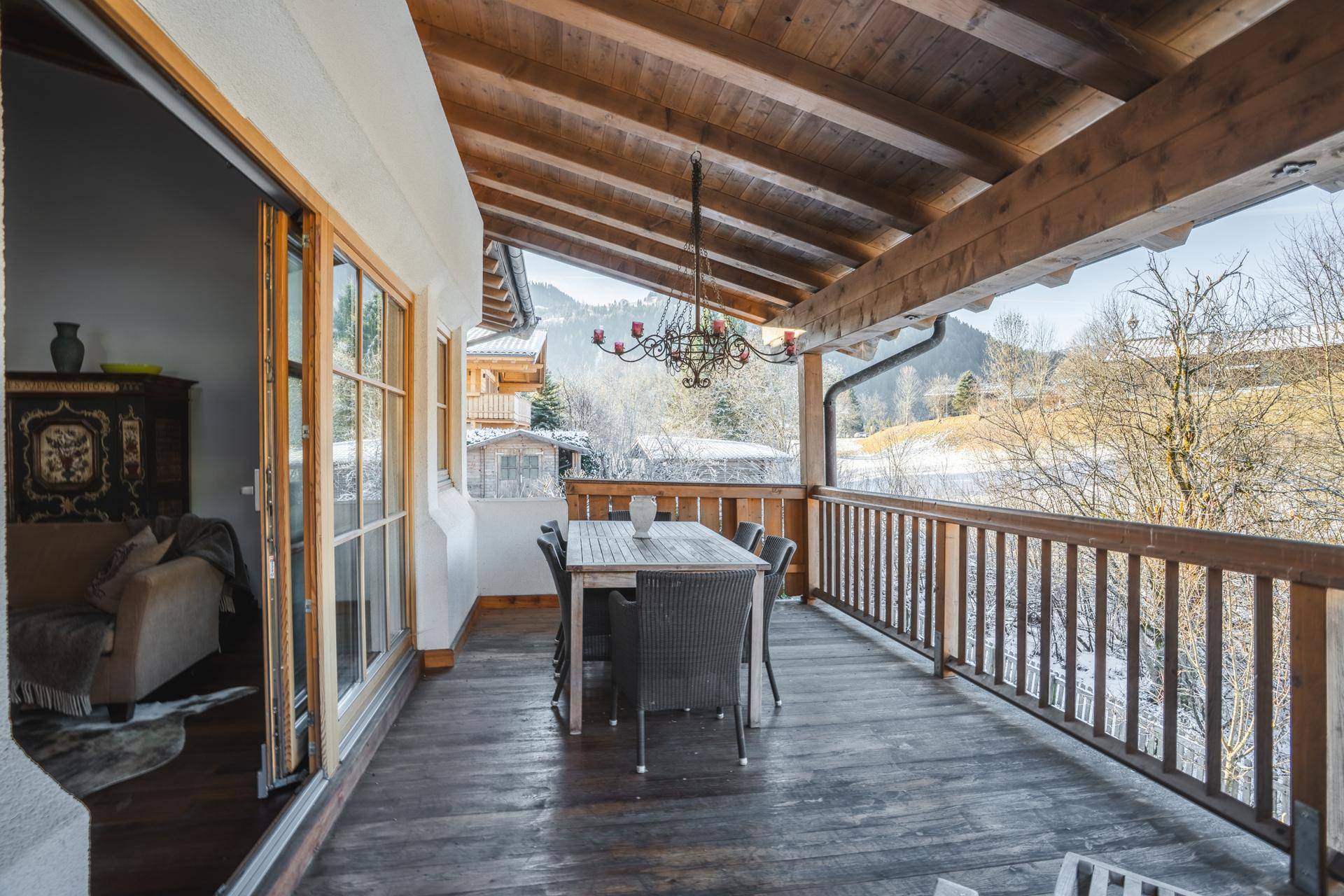 Großer überdachter Balkon mit Esstisch und Stühlen, bietet einen schönen Blick auf die Berge.