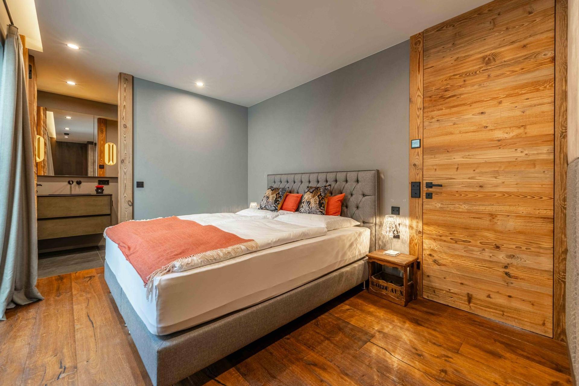 Komfortables Schlafzimmer mit Holzboden, gepolstertem Bett und Zugang zu einem eigenen Bad.