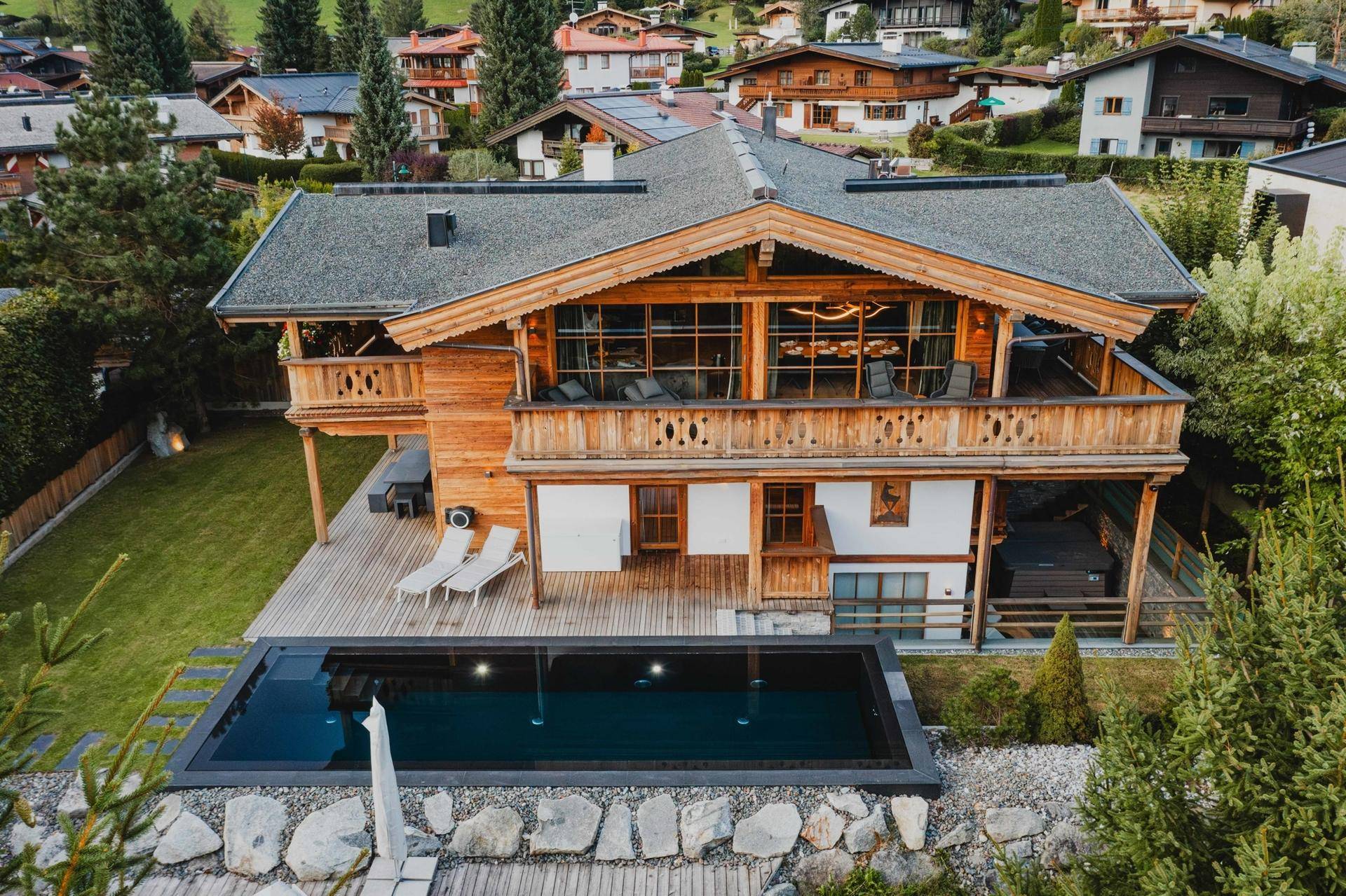 Vogelperspektive eines luxuriösen Chalets mit Pool, Garten und umliegender Wohnbebauung.