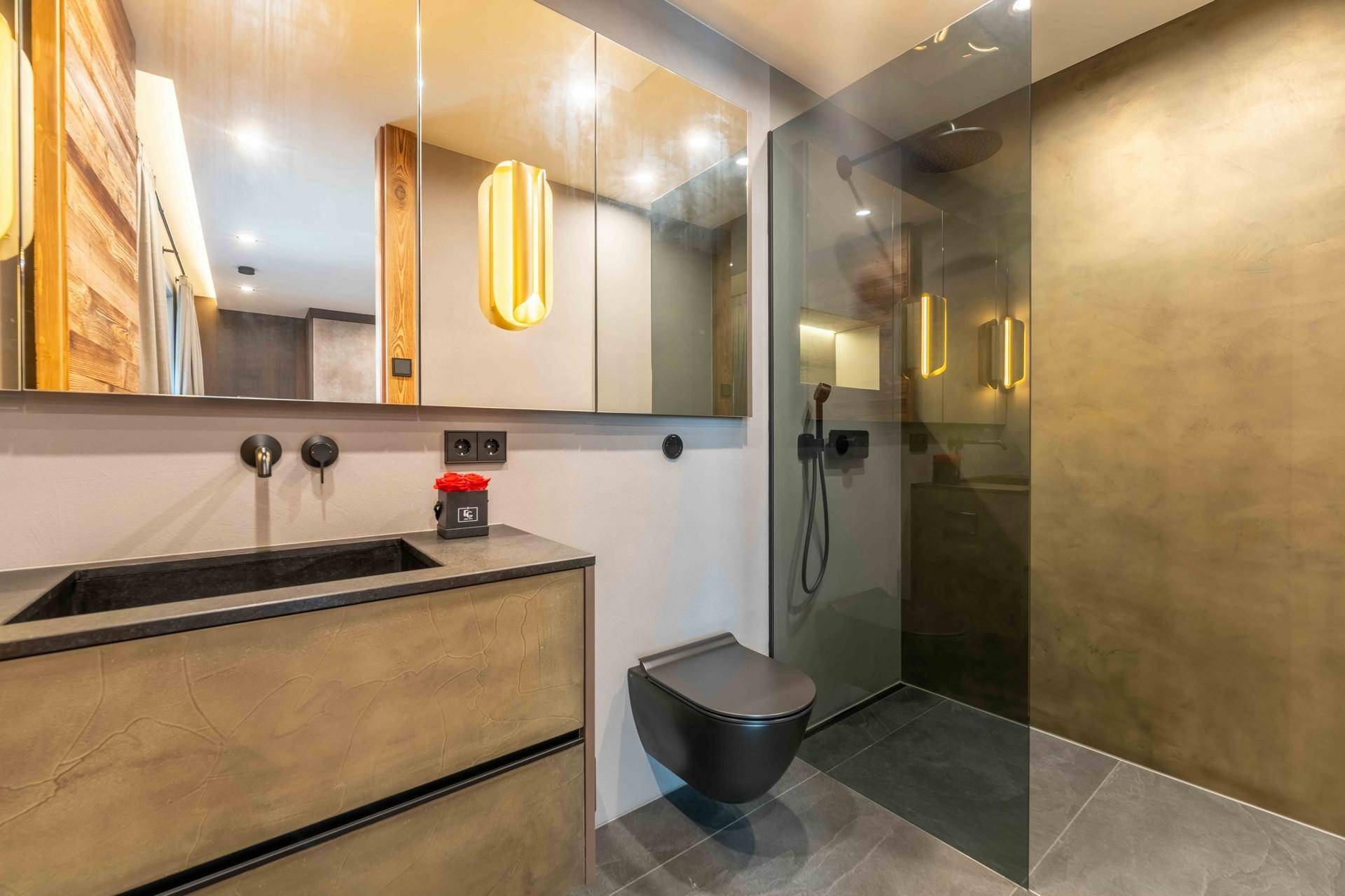 Modernes Badezimmer mit Einzelwaschbecken, begehbarer Dusche und eleganten dunklen Armaturen.